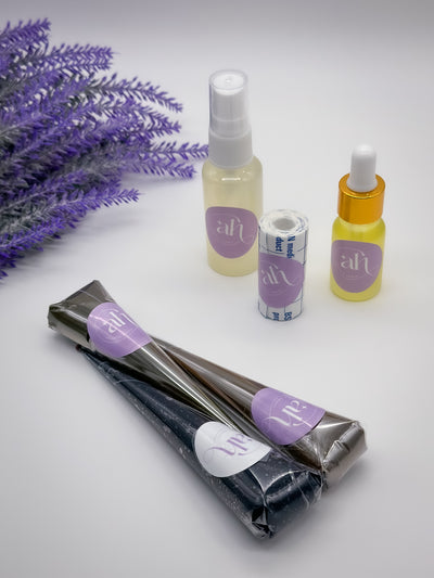 Two henna cones and one jagua cone bundle from Amarya Henna, placed beside an aftercare kit that includes a clear lemon sugar spray bottle, a roll of Mefix medical tape, and a small bottle of aftercare oil.