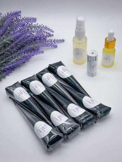 The image displays a set of Jagua cones alongside bottles of Lemon Sugar Sealant Spray and Aftercare Oil by Amarya Henna, all arranged on a surface with a lavender plant in the background.