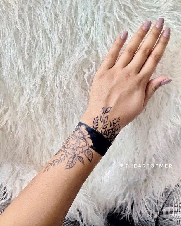 A woman's wrist with a delicate jagua tattoo featuring intricate floral patterns, applied using Amarya Henna cones