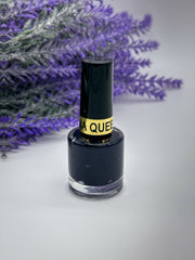 Back of a bottle of Queen Nail Henna in Deep Lavender (Lilac) color with a black cap, placed against a white background with lavender flowers in the background. Sold by Amarya Henna