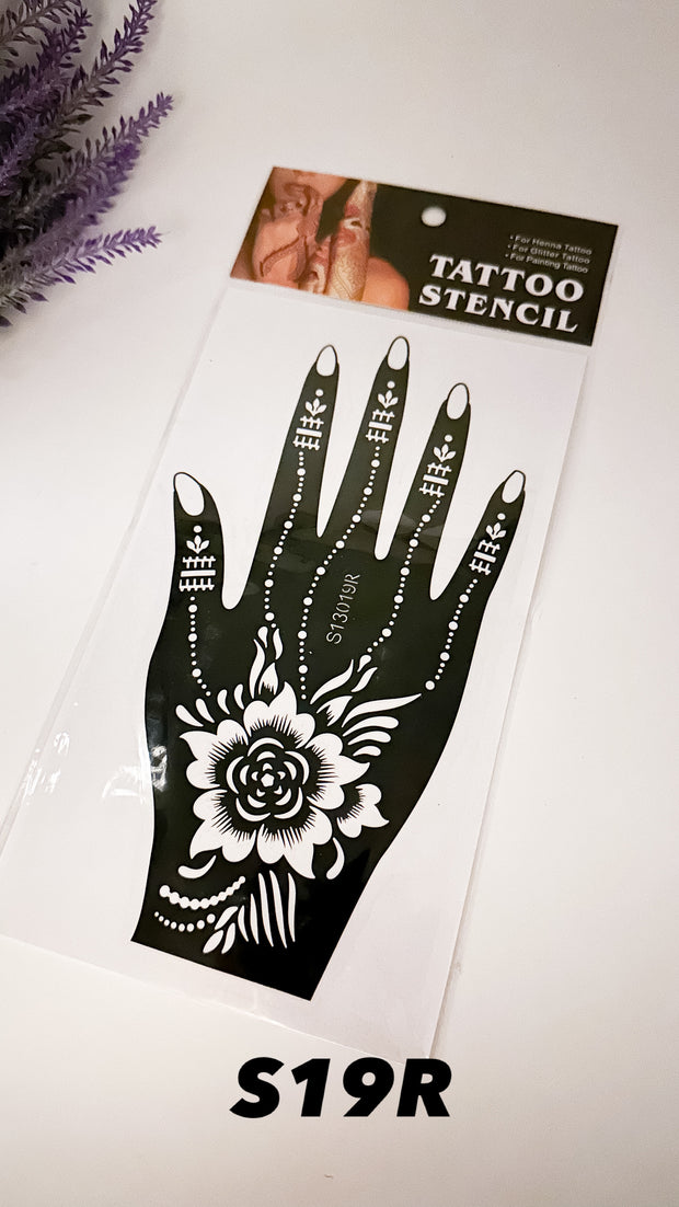 A black henna stencil design of a hand with a floral pattern, labeled 'S19R', on a clear plastic sheet.