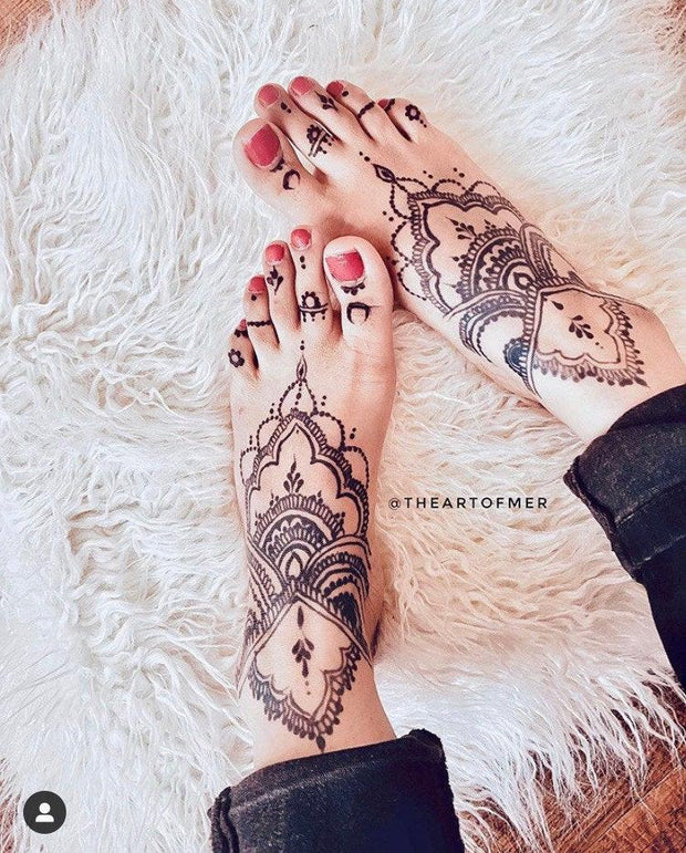 Fair light-skinned woman feet adorned with an intricate Jagua design, showcasing a deep blue-black stain created using Amarya Henna Jagua cones.